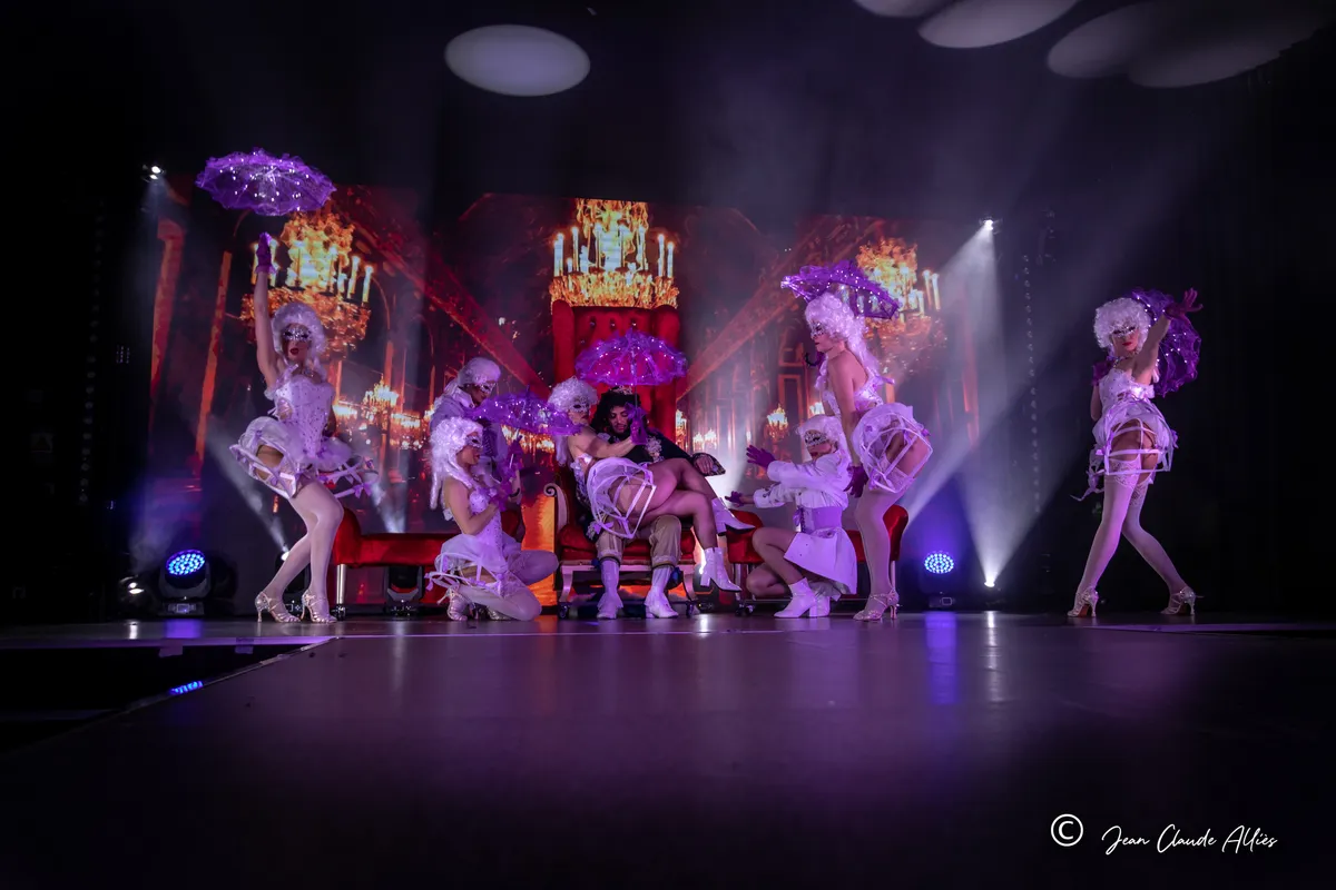Tableau de cour avec perruques blanches, costumes argentés et ombrelles violettes devant un décor de palais.