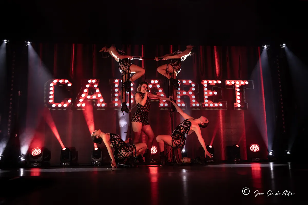 Troupe en noir composant un tableau en hauteur, les bras ouverts, devant les lettres lumineuses Cabaret.